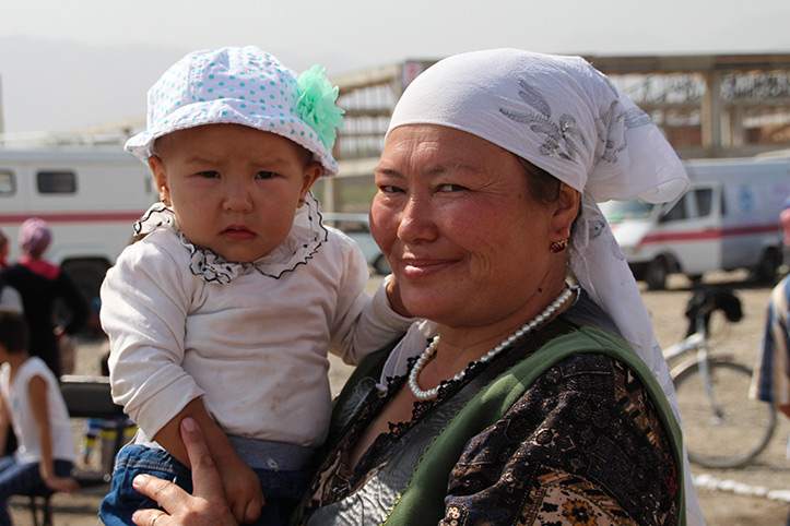 Kirgisische Frau hat Kleinkind im Arm 