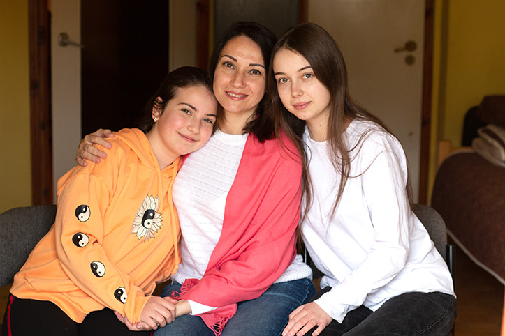 Zwei große Mädchen schmiegen sich an Mutter