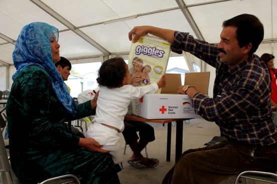 Eine Flüchtlingsfamilie ist mit Hilfsgütern zu sehen. Auf dem Paket steht "Giggles"