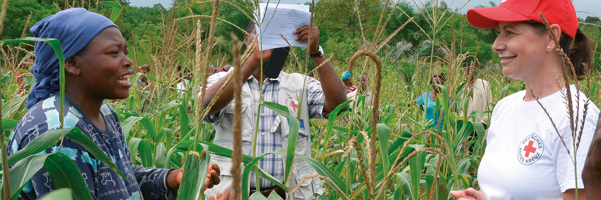 [Translate to Englisch:] Eine togolesische Frau mit einer DRK-Mitarbeiterin in einem Maisfeld