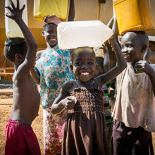 Kinder im Sudan tragen Wasser auf dem Kopf