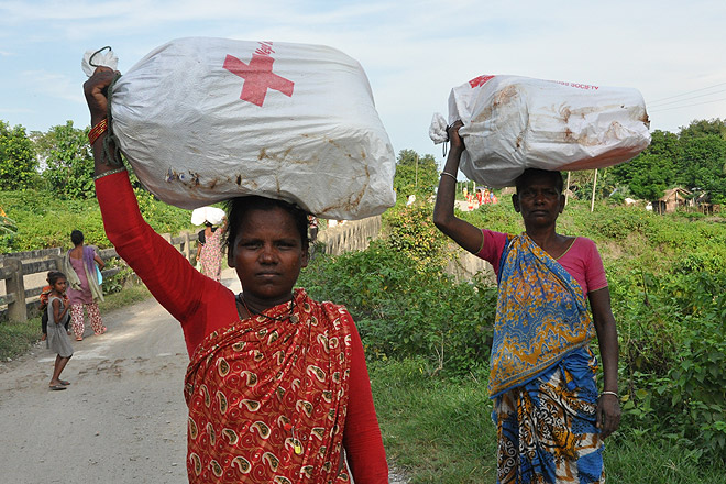 Zwei nepalesische Frauen tragen Hilfsgüter auf dem Kopf