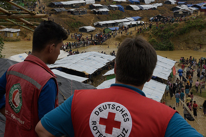 DRK weitet Hilfe für Rohingya aus Mitarbeiter des Roten Kreuzes schauen auf ein Flüchtlingslager der Rohingya