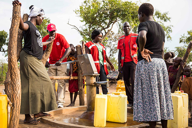 Hilfe für südsudanesische Flüchtlinge in Uganda Südsudanesische Flüchtlinge und Mitarbeiter des Ugandischen Roten Kreuzes, die mit einer Wasserpumpe Wasser aus einem instandgesetzten Brunnen holen.