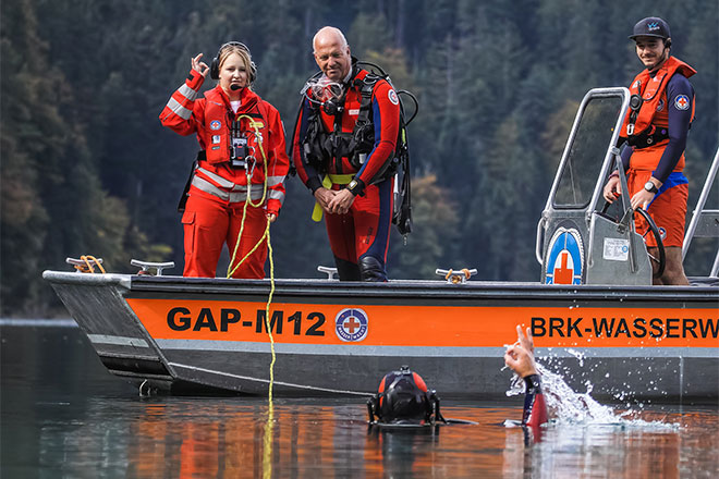 DRK-Wasserwacht-Ehrenamtliche auf Boot machen Zeichen